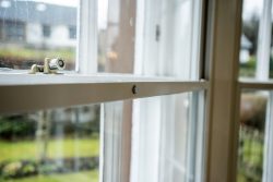 Push button on a vertical sliding secondary glazing unit